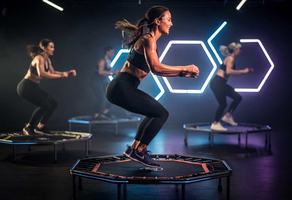 A trampoline rebounding class mid-bounce under blue and violet neon